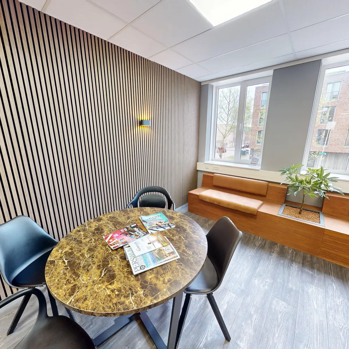 Waiting area with a wooden slatted wall, reading table and bench in Almere-Poort